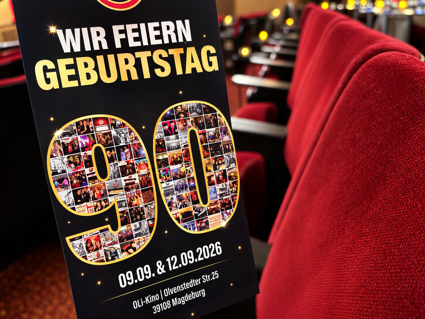 Jubiläumsplakat „Wir feiern Geburtstag – 90“ zwischen den roten Sesseln des OLi-Kinos.